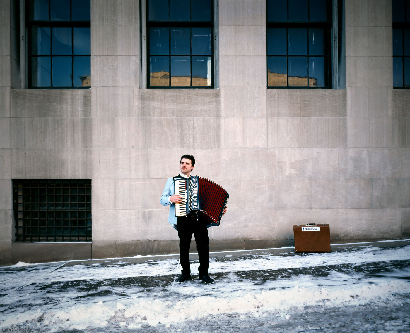 Busker playing accordion in snow portrait