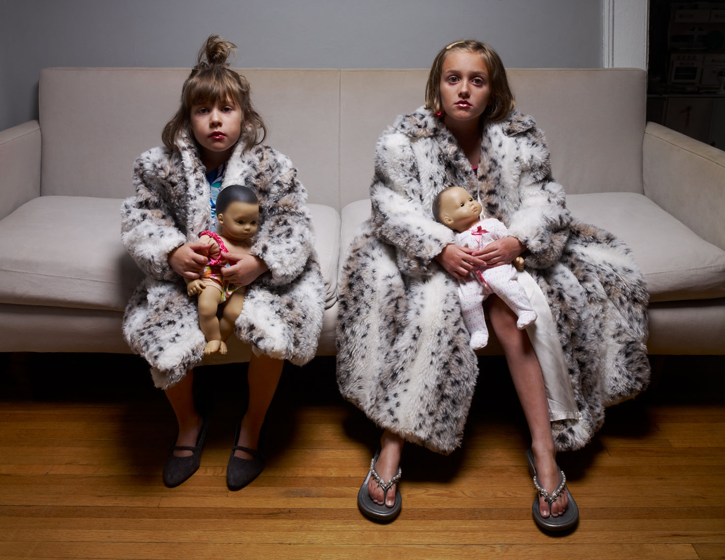 2 young sisters seated with fur coats and dolls portrait