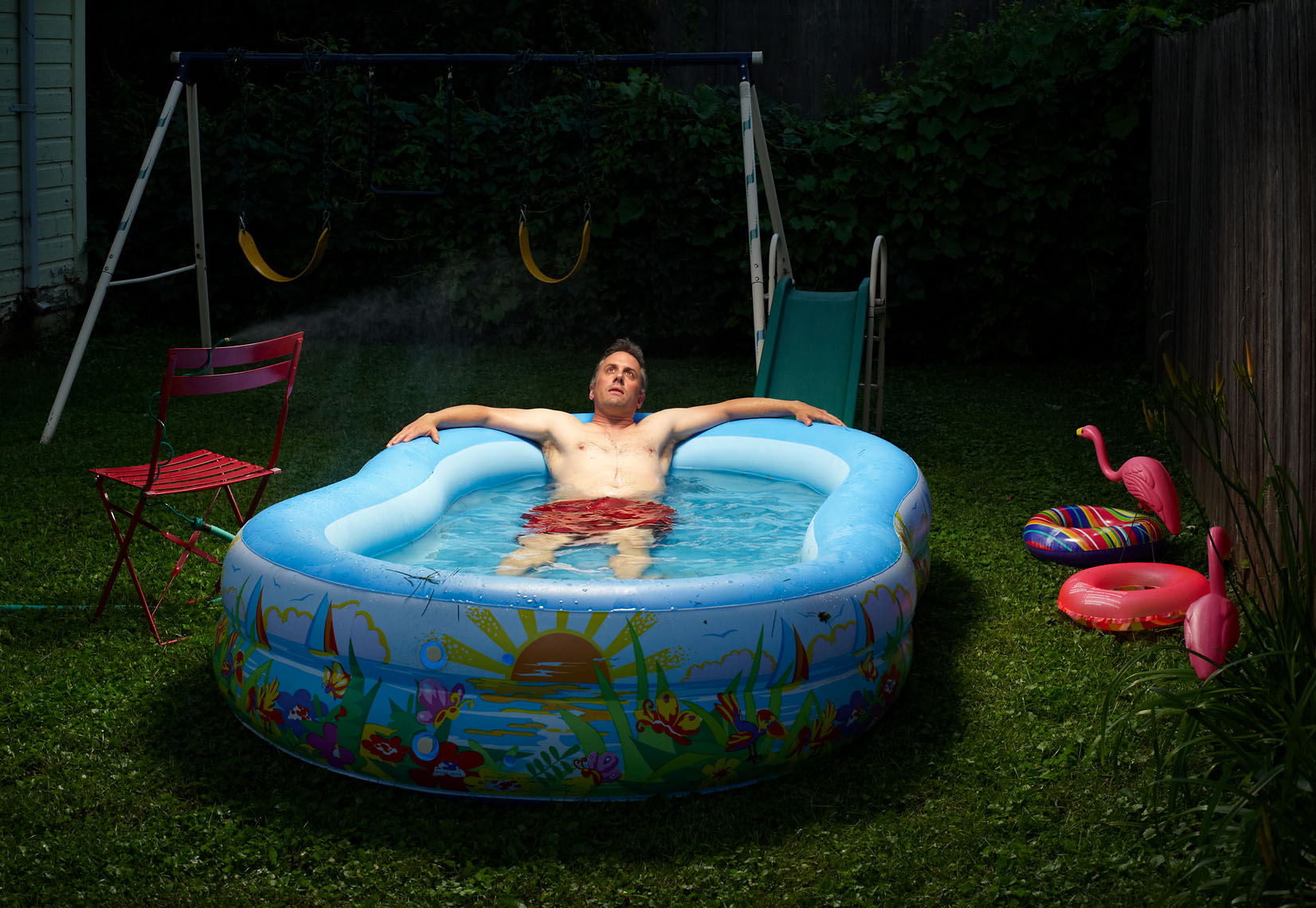 Middle aged man soaks in kiddie pool lifestyle